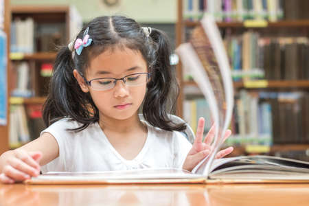 School education and literacy concept with Asian girl kid student learning and reading book in library or classroomの写真素材