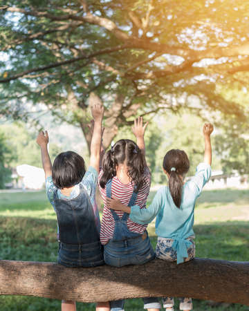 Happy kids in the park having fun sitting under tree shade playing together enjoying good memory and moment of girl student lifestyle with friends in school time day for children friendship conceptの写真素材
