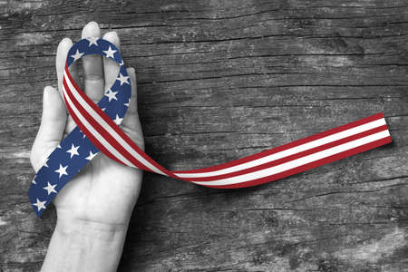 American flag pattern awareness ribbon color splashed on human hand grunge background: United states of america public holiday USA national day, nationalism raising US nation support campaign conceptの写真素材