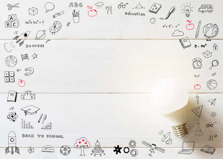 Innovative creative idea concept with lightbulb and school doodle on white wood boardの写真素材