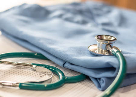 Surgical doctor gown on working table in medical clinic with stethoscope for heart and cardiological diagnostic exam and surgeon's or cardiologist operation workの写真素材