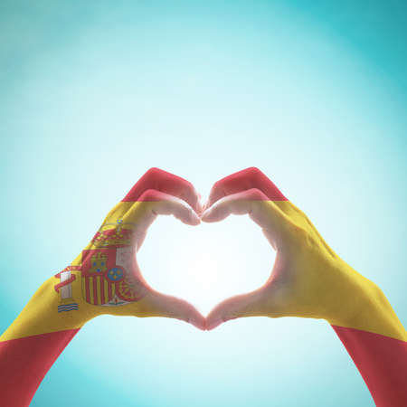 Spain national flag pattern on people's hand in heart shape   on sky backgroundの写真素材