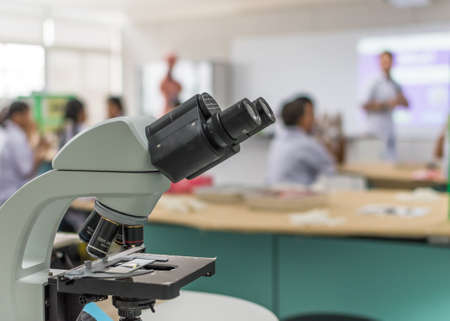 Biology or chemistry science class study with microscope and blur background of school student group learning in blurry lab classroom with teacher for education conceptの写真素材