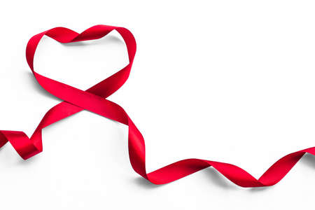 Red satin ribbon bow in heart shape isolated on white background (clipping path), symbolic concept for National heart monthの写真素材