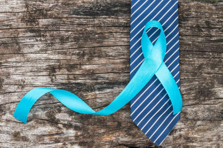 Prostate cancer awareness concept with light blue ribbon on necktie and old aged wood for men's...