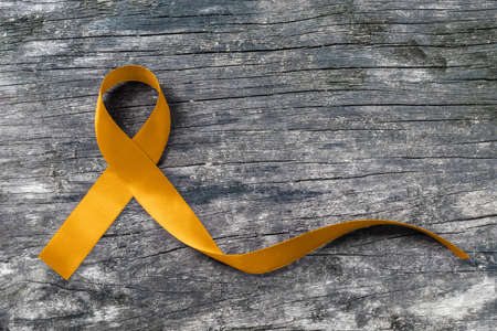 Gold ribbon awareness symbolic color for Childhood cancer on old aged woodの写真素材