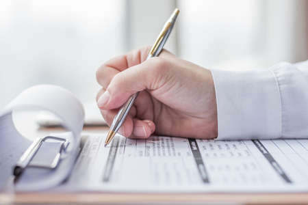 Applicant filling in company application form document applying for job, or registering claim for health insuranceの写真素材