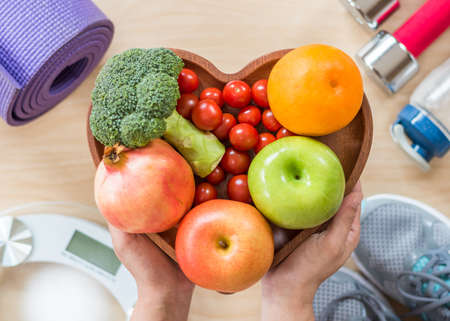 Healthy lifestyle concept, clean food good health dietary in heart dish with sporty gym aerobic body exercise workout training class equipment, weight scale and sports shoes in fitness centerの写真素材