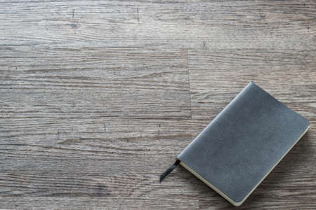 Mockup close diary book with blank black leather cover template paper texture on dark grey wood tableの写真素材