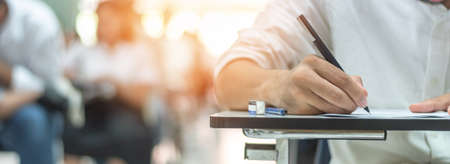 School exam student's taking educational admission test in class, thinking hard, writing answer in university classroom, education and world literacy day conceptの写真素材