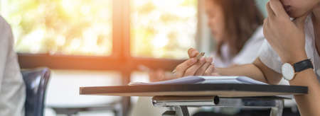 School exam student's taking educational admission test in class, thinking hard, writing answer in university classroom, education and world literacy day conceptの写真素材