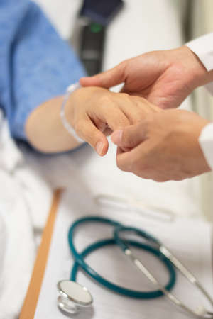 Patient on bed with doctor holding hands for nursing, medical health care, caregiver and in-patient ward healthcare conceptの写真素材