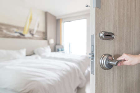 Hotel room door opened unlock to guest bedroom interior view with blur background of modern comfort bed luxury high quality living space for travelerの写真素材