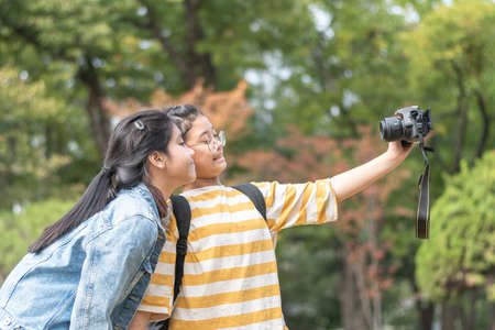 Girls friends, teenager school students with digital camera selfie in the park for vlog, video blog for traveling reviewの写真素材