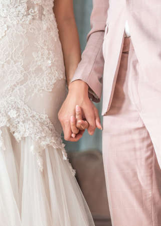 Married couple bride and groom holding hands in wedding ceremony for marriage conceptの写真素材