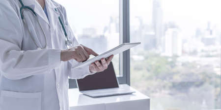 Doctor or physician holding mobile digital tablet for patient's health record in medical clinic or hospital office for professional online and emergency healthcare assistance serviceの写真素材