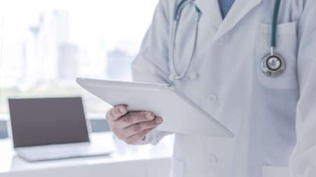 Doctor or physician holding mobile digital tablet for patient's health record in medical clinic or hospital office for professional online and emergency healthcare assistance serviceの写真素材