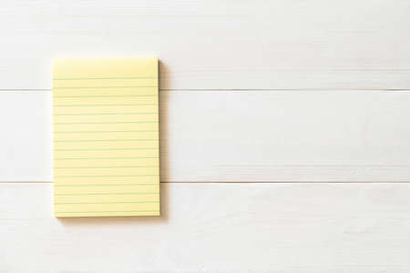 Blank pastel yellow color reminder paper pad with horizontal line stripes copy space on white pine woodの写真素材
