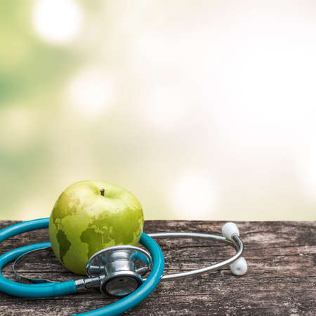 World health day symbolic concept with map on healthy nutritional apple with doctor's stethoscopeの写真素材