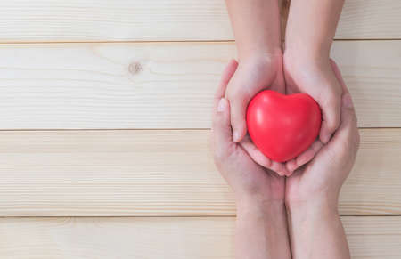 I love you Mom, Mother's Day celebration with woman holds young kid's hands supporting red heart gift, and charity donation for nursing children conceptの写真素材