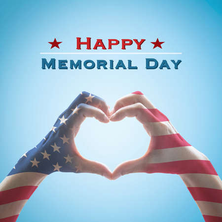 Happy memorial day with America flag pattern on people hands in heart shape isolated on blue sky backgroundの写真素材