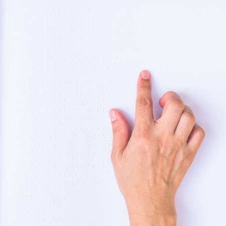 Braille book with visual impaired, low vision, blind person's hand/ finger touching paper texture reading the signの写真素材