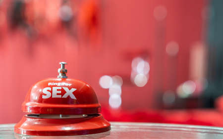 Sex shop background concept with ring bell and blur sexy red erotic bed room for adult escort service business, sex call and men clubの写真素材