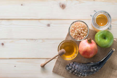 Rosh Hashanah (Hashana)  (jewish New Year holiday) and Yom Kippur concept with Ram shofar (horn) and traditional food, apple, honey, pomegranate fruit flat lay on wood table background from top viewの写真素材