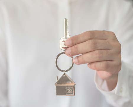 Home buyer insurance concept with house key in broker agent or salesman person's hand giving to customerの写真素材