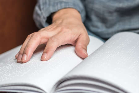 Braille book with visual impaired, low vision, blind person's hand/ finger touching paper texture reading the signの写真素材