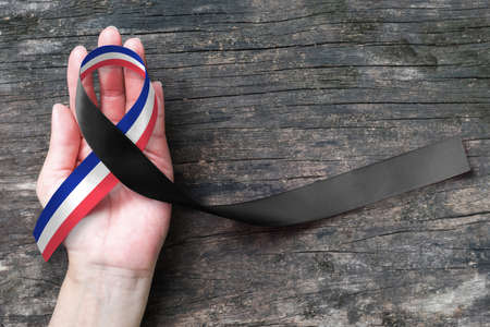 Red white blue France national flag pattern and black ribbon on human hand support on old aged backgroundの写真素材