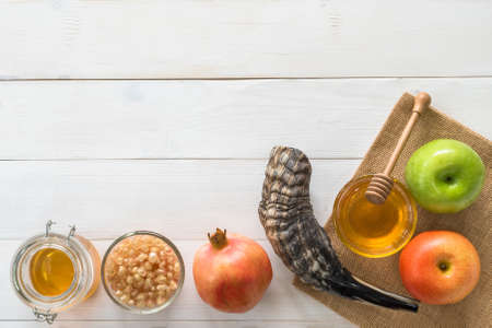 Rosh Hashanah (Hashana)  (jewish New Year holiday) and Yom Kippur concept with Ram shofar (horn) and traditional food, apple, honey, pomegranate fruit flat lay on wood table background from top viewの写真素材