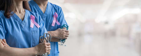 Breast cancer awareness pink ribbon raising awareness on women's health and female illness in October month with bow color on male and female surgical doctor gown in clinic or hospitalの写真素材