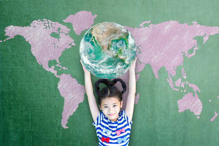 Happy Asian girl child student raising globe on school chalkboard for world literacy and gender equality concept.の写真素材