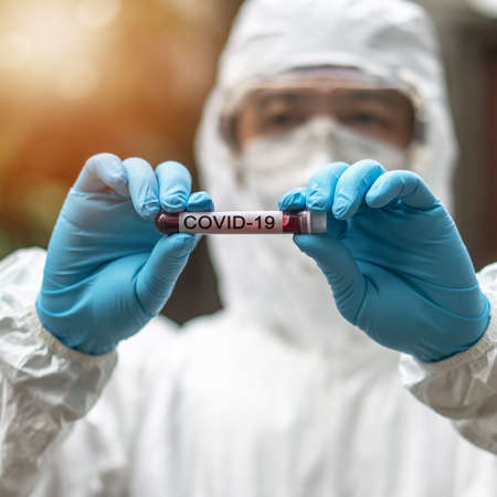COVID-19, Corona Virus epidemic disease with doctor in PPE Personal Protective Equipment holding blood test tubeの写真素材