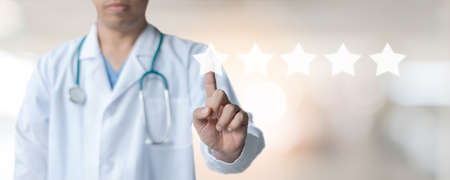 Medical doctor with pointing finger on virtual screen with 5 stars sastisfaction rating and copy space on blur hospital backgroundの写真素材