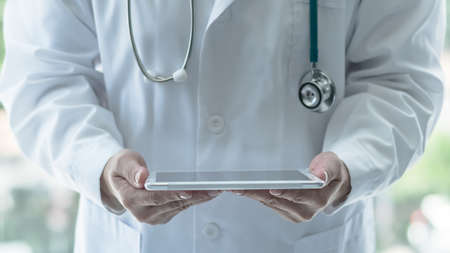 Telemedicine by medical doctor or physician consulting patientâs health telehealth online using mobile tablet in clinic or hospital for professional digital emergency healthcare assistance serviceの写真素材