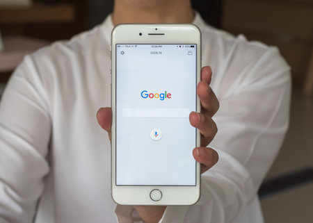 BANGKOK, THAILAND. July 4, 2017: Google application search engine sign up page on mobile app touchscreen on iphone in business person's hand and on computer screen displayのeditorial素材