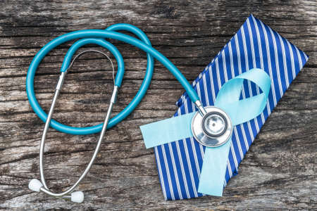 Prostate cancer blue awareness ribbon for men health concept with light blue bow color on medical health insurance claim form and stethoscope on doctor desk backgroundの写真素材