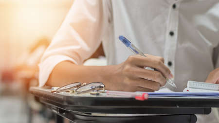 Exam at school with student's taking educational admission test in class, thinking hard, writing answer in university classroom, education and world literacy day conceptの写真素材