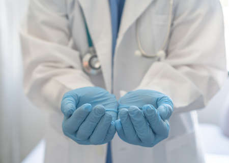 Medical doctor or surgeon with empty hands in hygience lab gloves offering or holding copy space for health care practice, nursing, organ donation, hospital csr, or clinical charity conceptの写真素材
