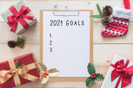 2021 Goals for new year calendar planner note on clipboard with Christmas background of gift box, red satin ribbon decoration on white pine wood, winter seasonal holiday celebrationの写真素材