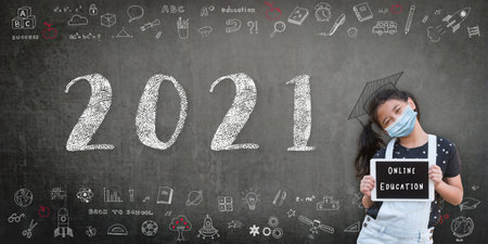 2021 online class with student girl kid with face mask for covid-19 protection with e-learning digital tablet and happy new school year academic calendar greeting on teacher's blackboardの写真素材