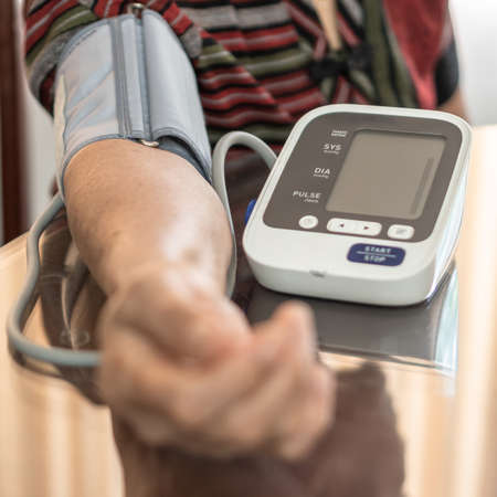 High blood pressure, hypertension and cardiovascular disease in aged senior older elderly woman with bp, heart rate, digital pulse check equipment for medical geriatric awareness in heart strokeの写真素材