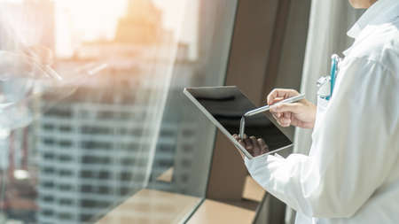 Telehealth and telemedicine by medical doctor or physician consulting patientâs health online using mobile digital tablet in hospital for professional emergency tele-healthcare assistance serviceの写真素材