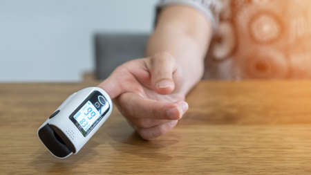 Oximeter, pulse rate and blood oxegen level measurement on figertip of woman patient, medical equipment for monitoring heart rate and oxyhemoglobin saturation check by self test at homeの写真素材