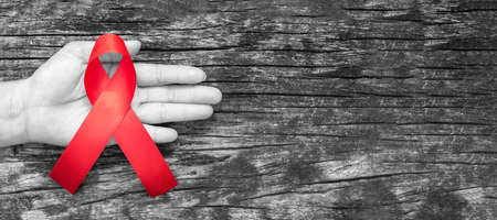 aids day and national HIV AIDS and ageing awareness month with red ribbon on helping hand (isolated with   on white background)の写真素材