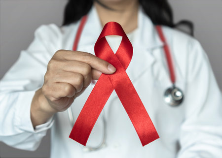 World aids day and national HIV AIDS and ageing awareness month in December with red ribbon on medical or surgical doctor's handの写真素材