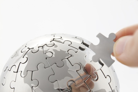 business concept with a hand building puzzle globe on white, space for messages の写真素材