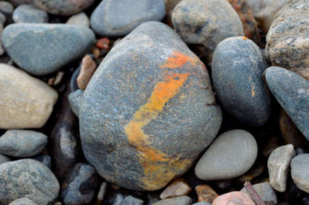 River rock with single curvy orange stripeの写真素材
